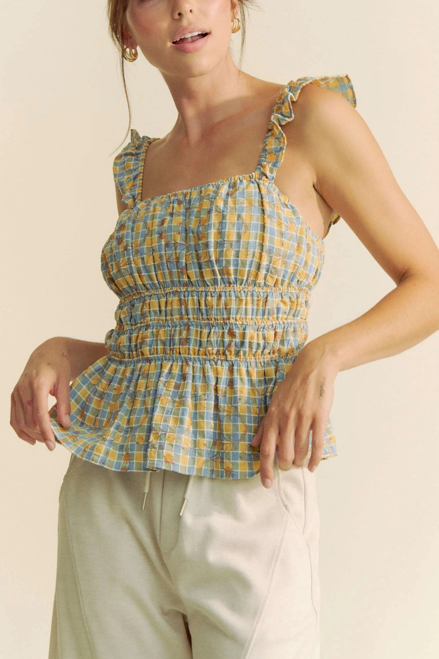 Model wearing plaid smocked top with ruffle straps front view