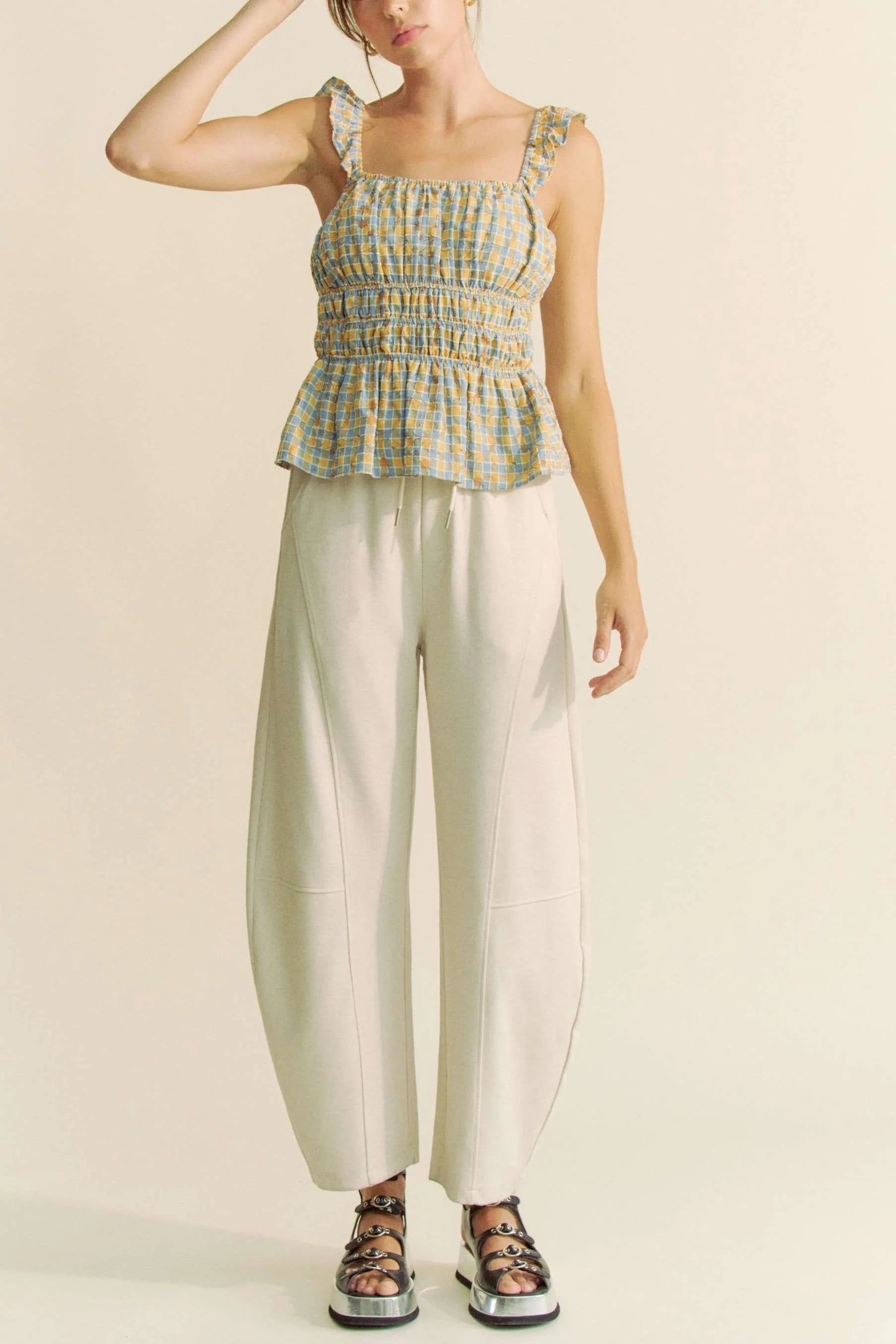 Model wearing plaid smocked top with ruffle straps front view with pantst
