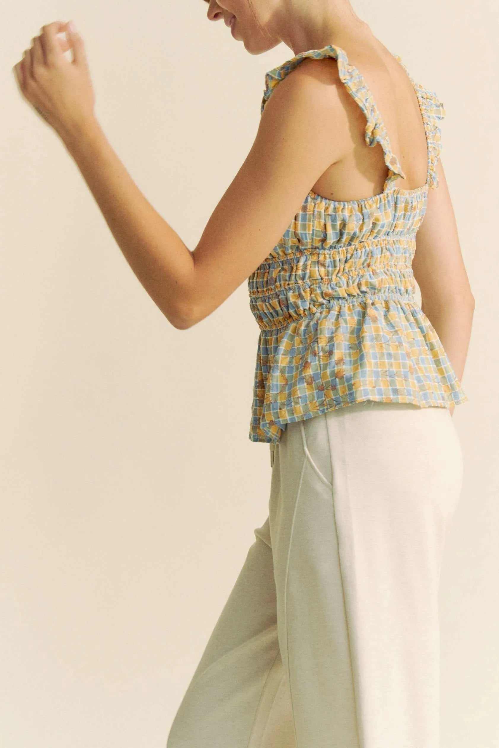 Model wearing plaid smocked top with ruffle straps side view
