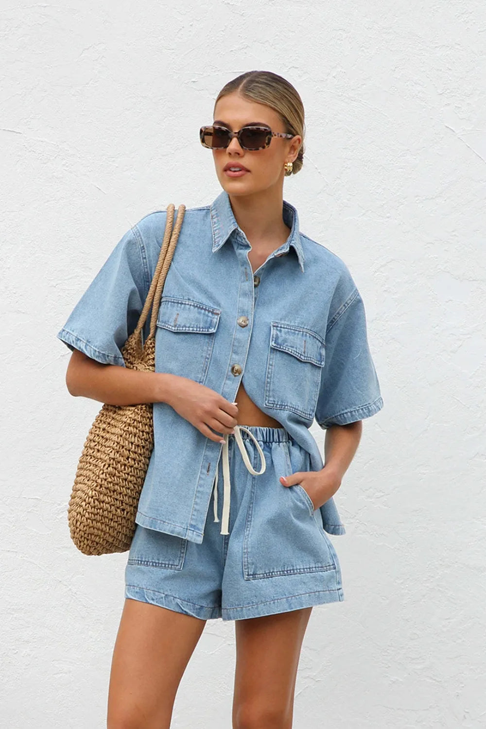 Woman wearing a Two-piece denim shirt and shorts summer co-ord against a white background