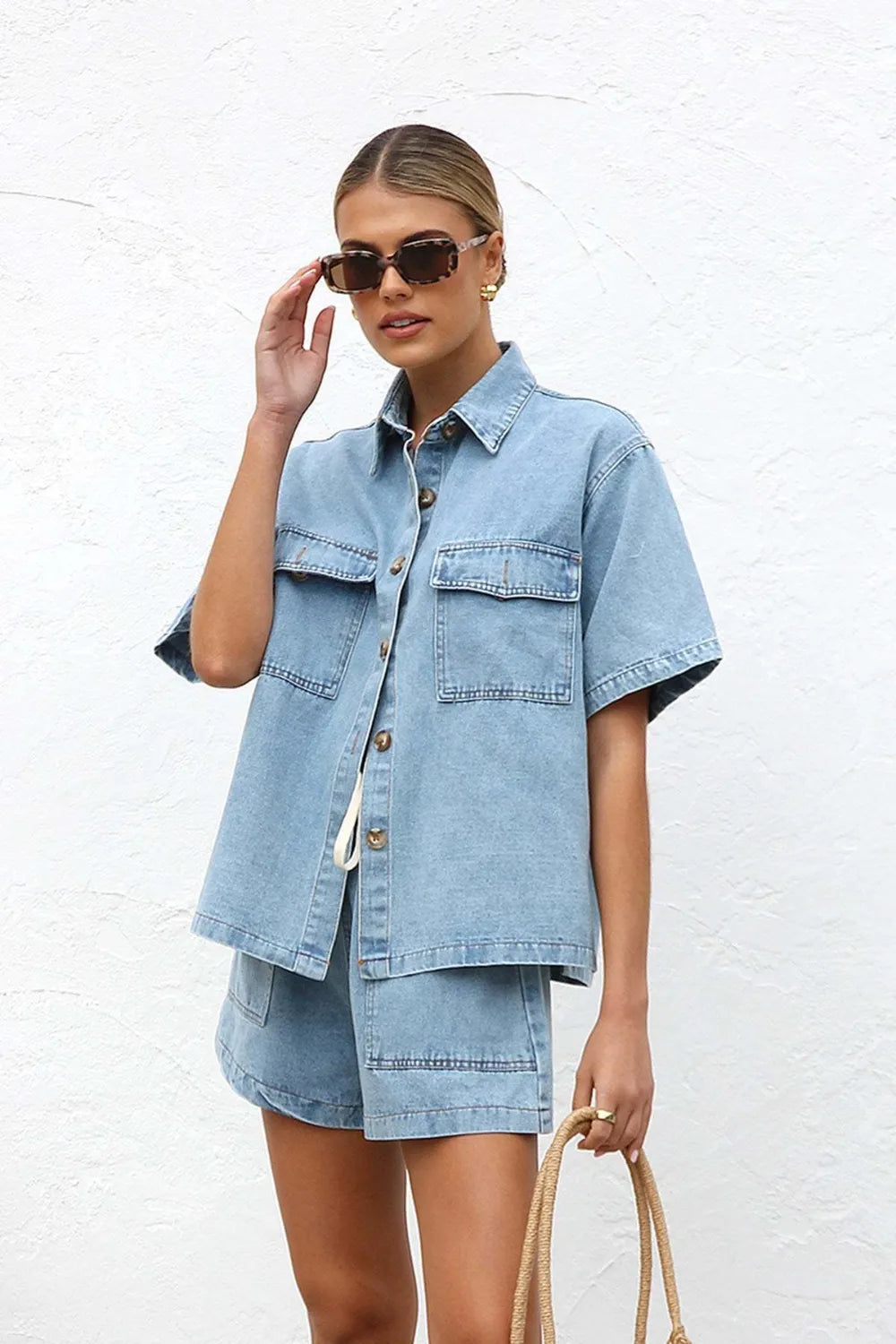 Woman wearing a light blue denim outfit  set against a white background