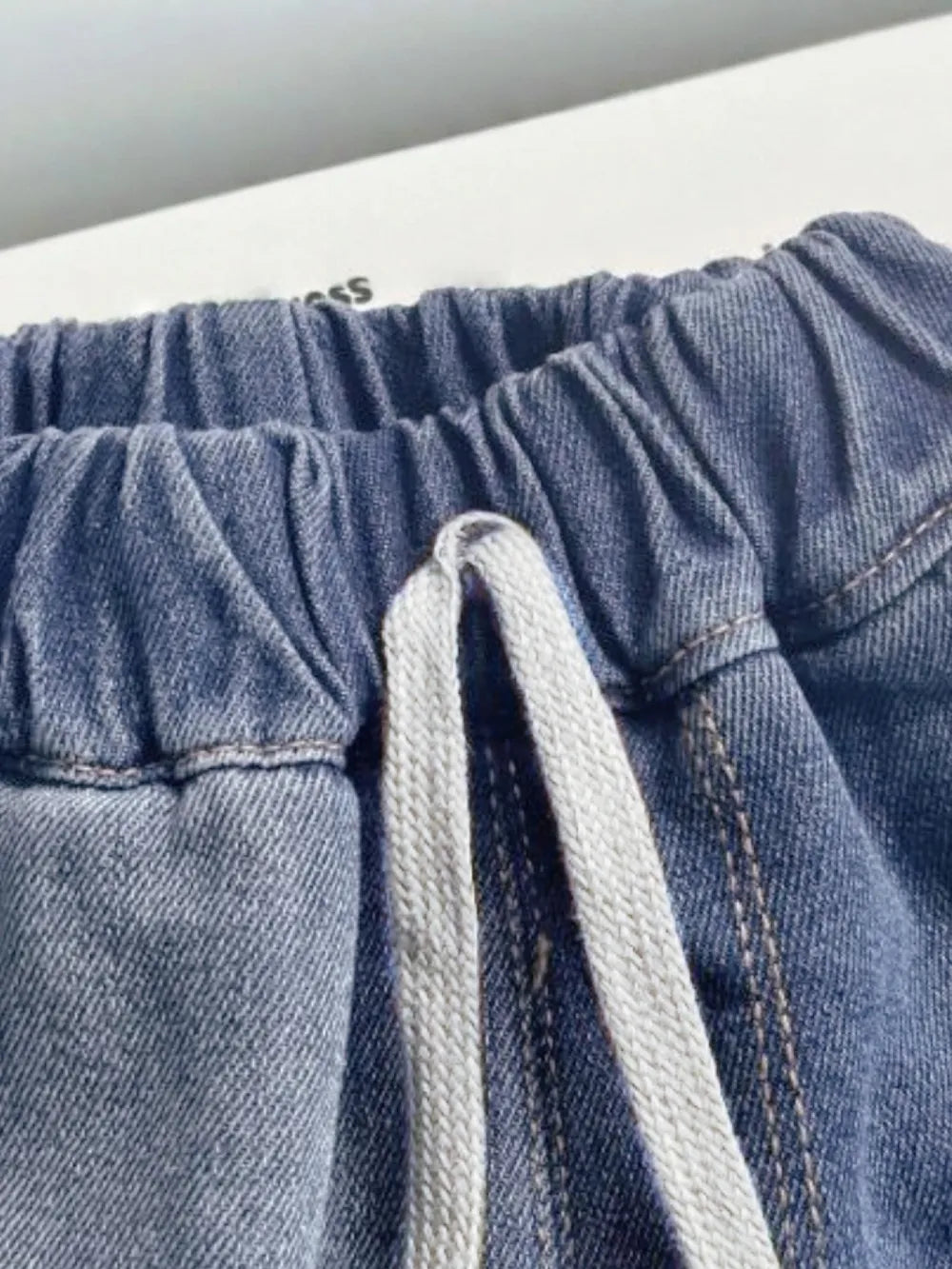 Close-up of blue denim summer shorts with a drawstring on a white background