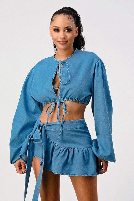 woman wearing a blue adjustable tie front denim crop top with matching ruffle mini skirt