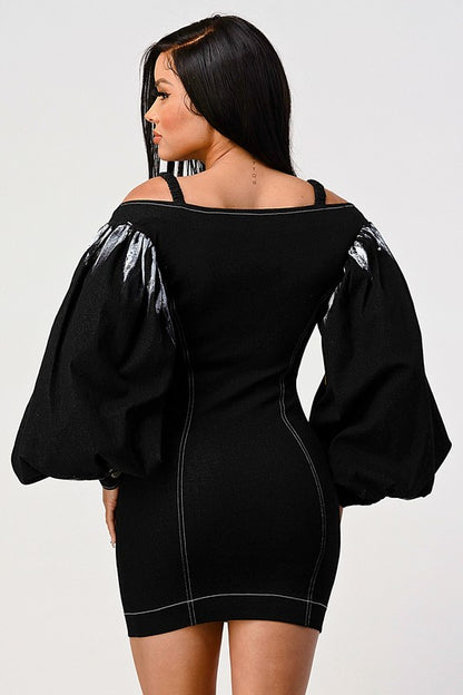 back view of woman wearing a black front zip-up black denim bodycon mini dress with off-shoulder neckline and lantern tie dye long sleeves 