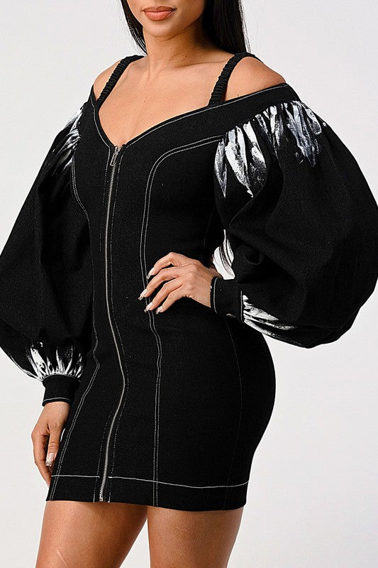 side view of woman wearing a black front zip-up black denim bodycon mini dress with off-shoulder neckline and lantern tie dye long sleeves 