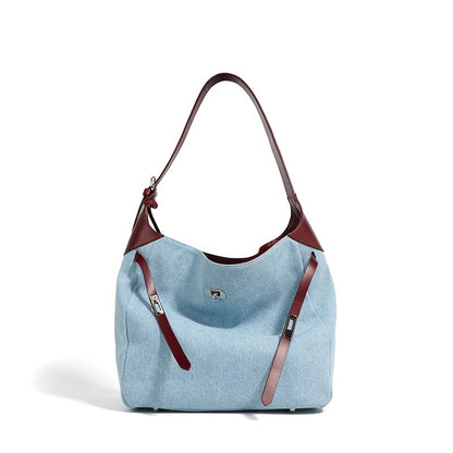 Light blue denim handbag with burgundy genuine leather straps on a white background