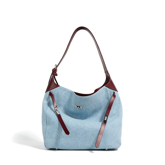 Light blue denim handbag with burgundy genuine leather straps on a white background