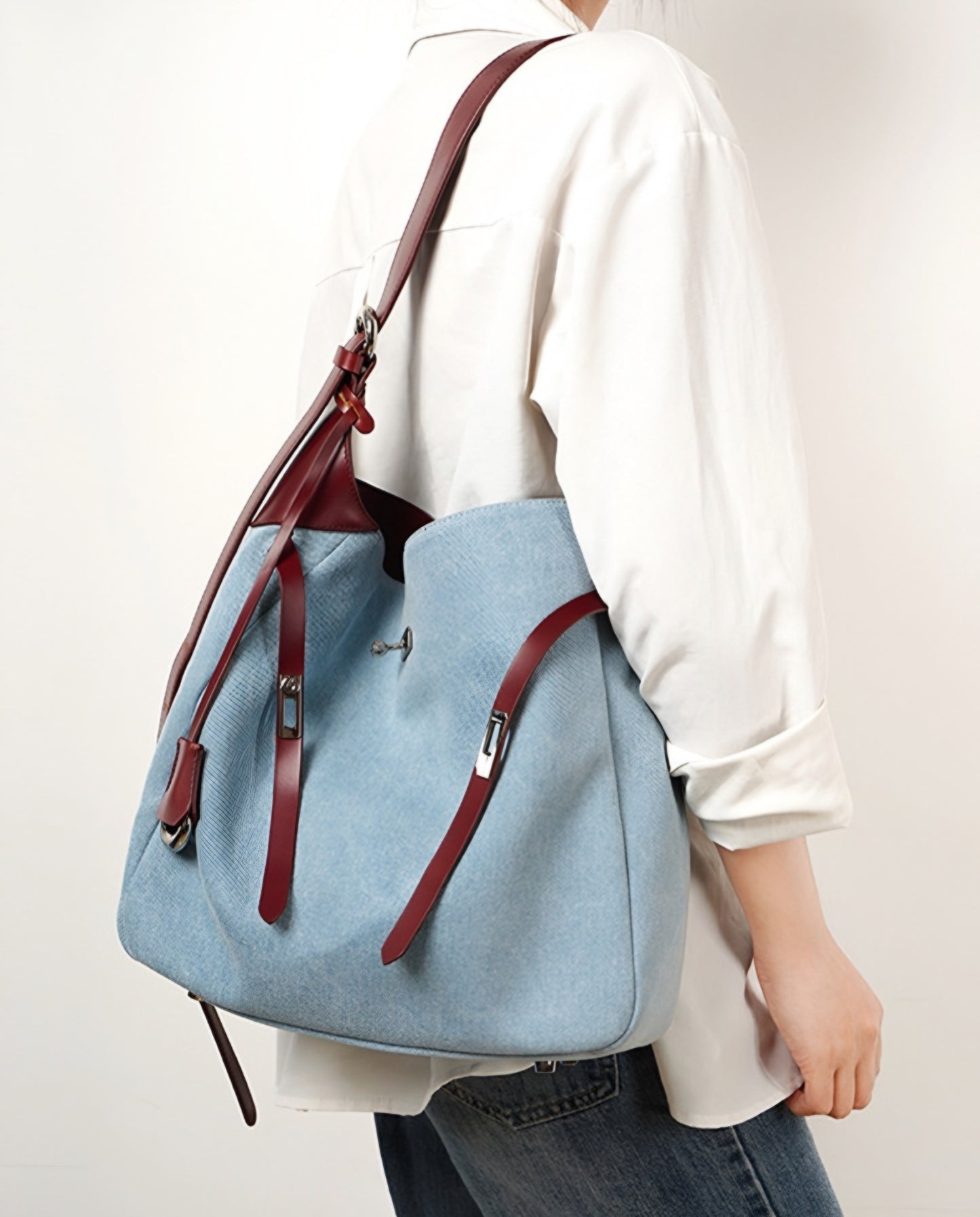 Woman carrying a light blue Denim & Genuine Leather Contrast Tote on a plain background