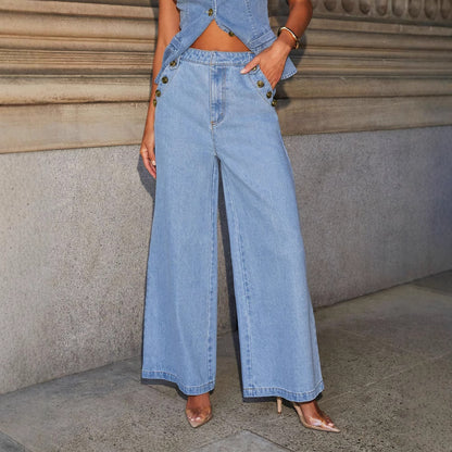 Woman posing in a high waist blue denim outfit with wide-leg jeans and a matching top against a stone wall.
