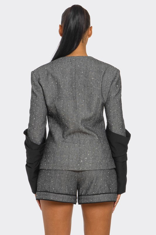 Woman wearing gray and black tweed blazer and high waist shorts tailored two piece set with shimmer detail on a white background back view