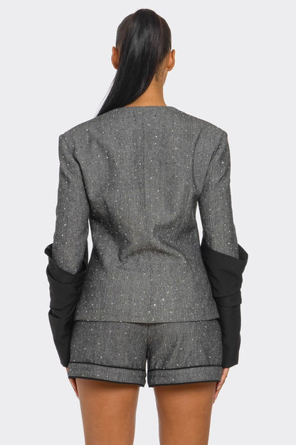 Woman wearing gray and black tweed blazer and high waist shorts tailored two piece set with shimmer detail on a white background back view