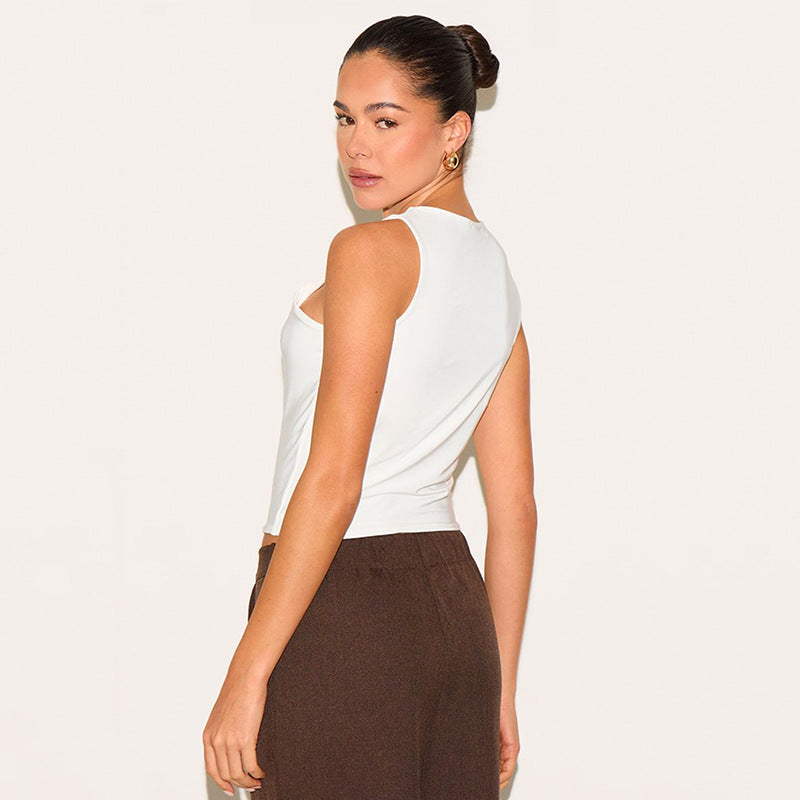 Woman wearing a white sleeveless top and brown pants on a plain background