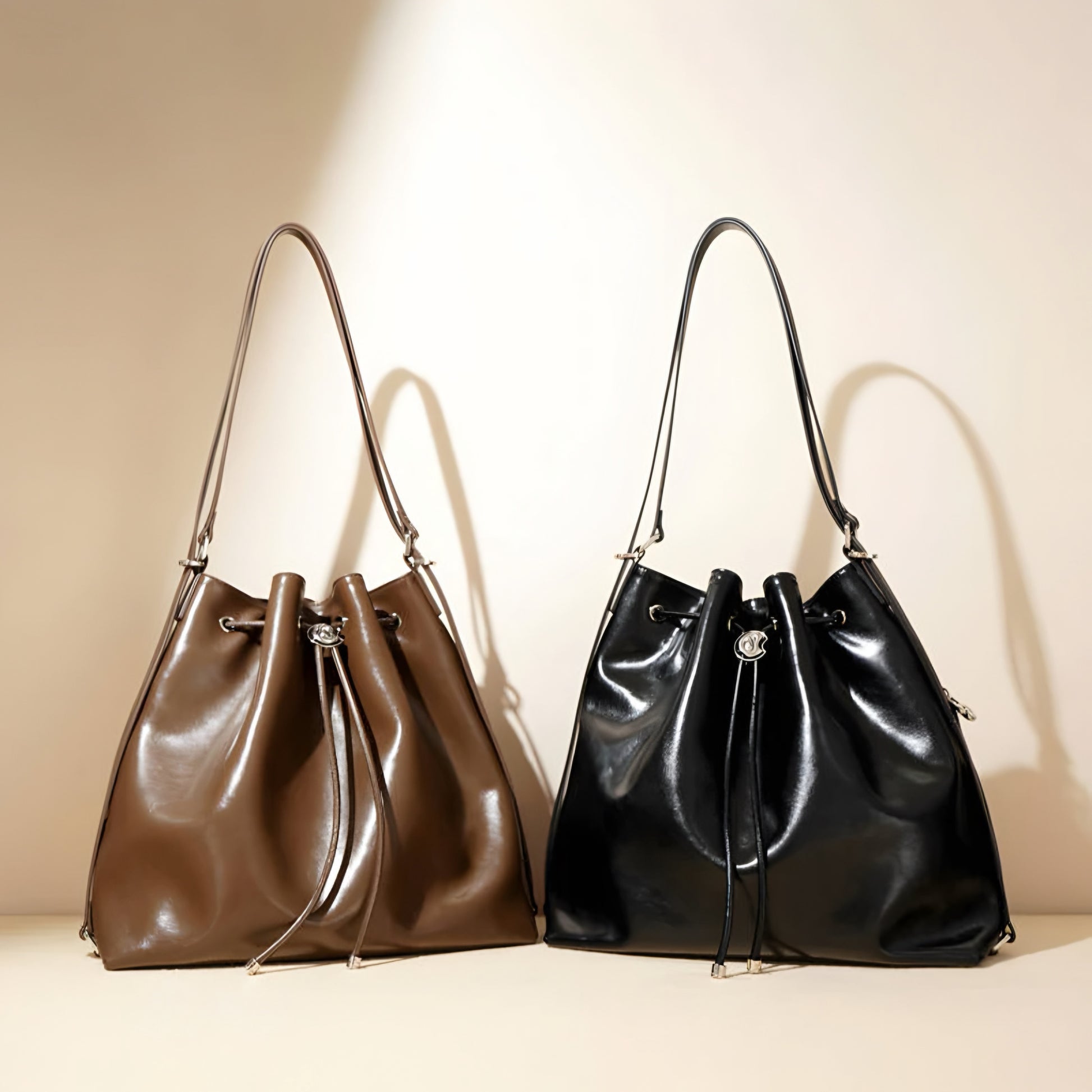 Brown and black genuine leather drawstring bucket shoulder bags on a beige background