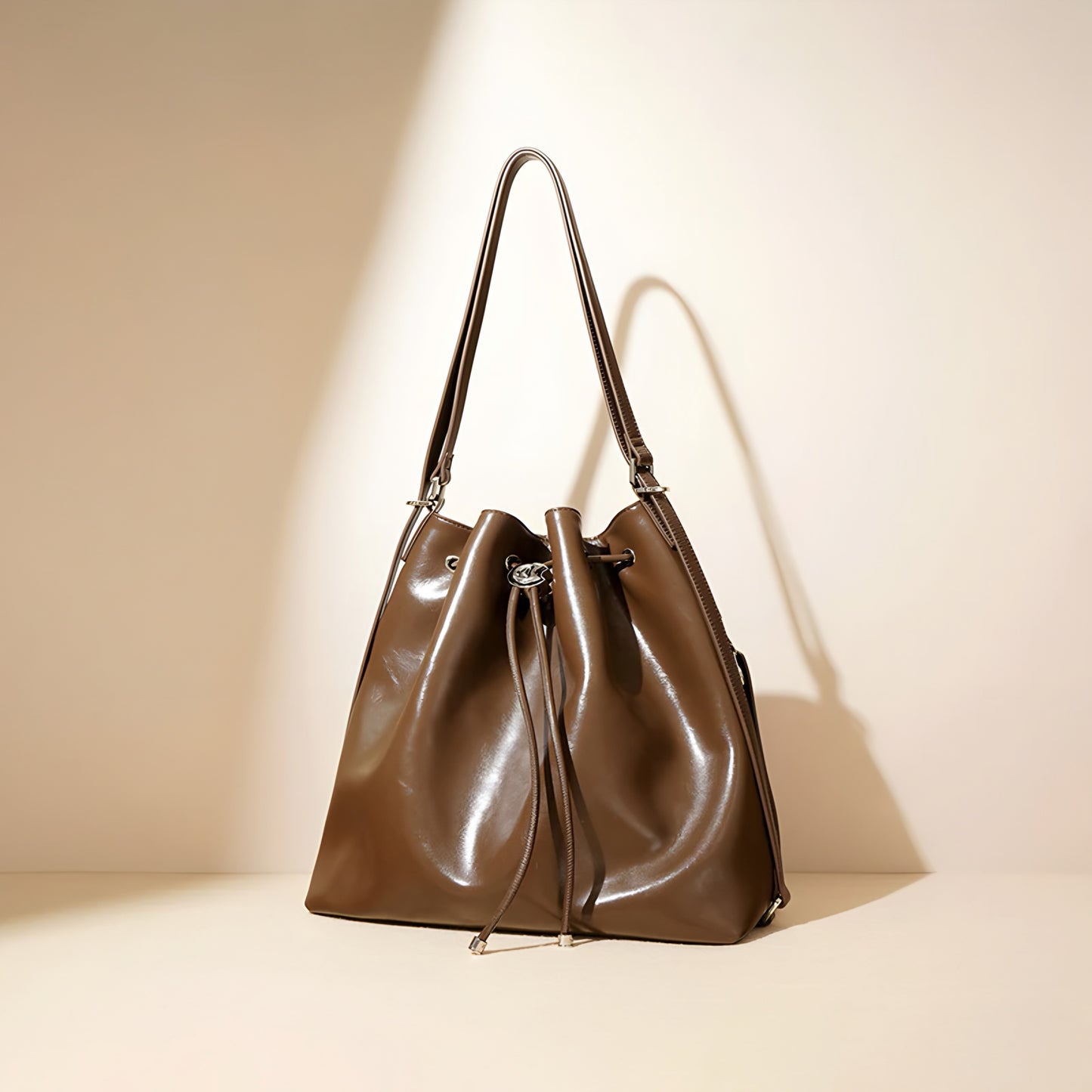 Brown genuine leather drawstring bucket shoulder handbag on a beige background