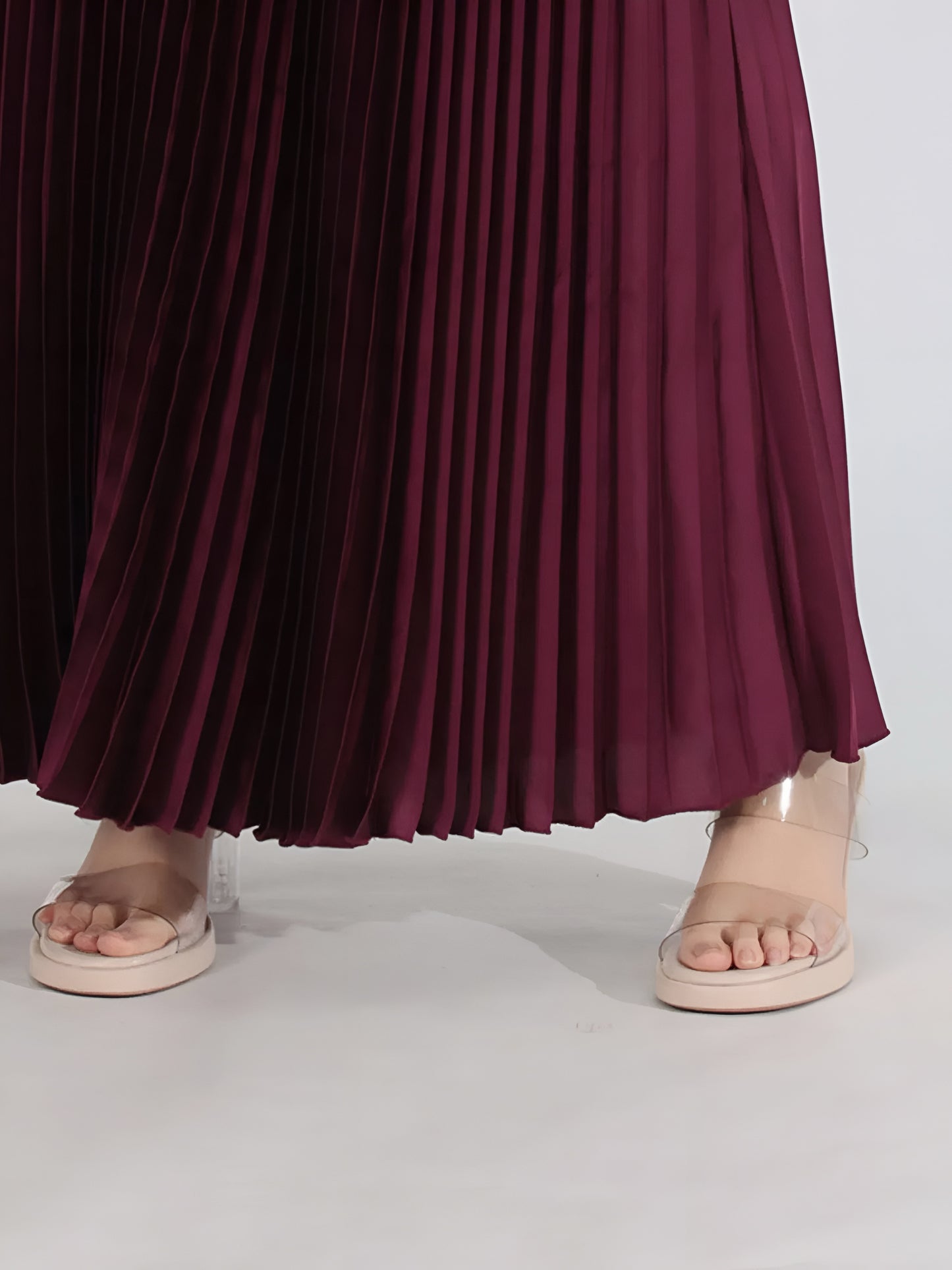 Close up of flowy pleated burgundy maxi skirt for two piece formal outfit set on a white background