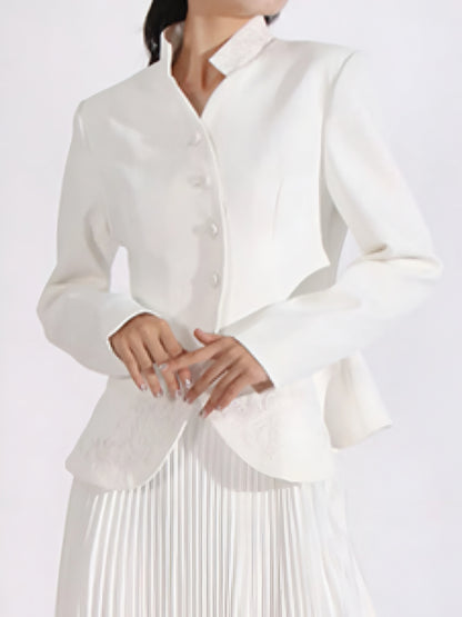 Close up of white blouse with long sleeves  and embroidered detail worn by a woman on a white background