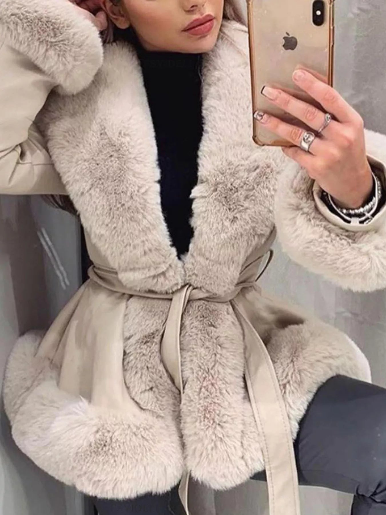 woman wearing a beige coat with fur collar taking a selfie.