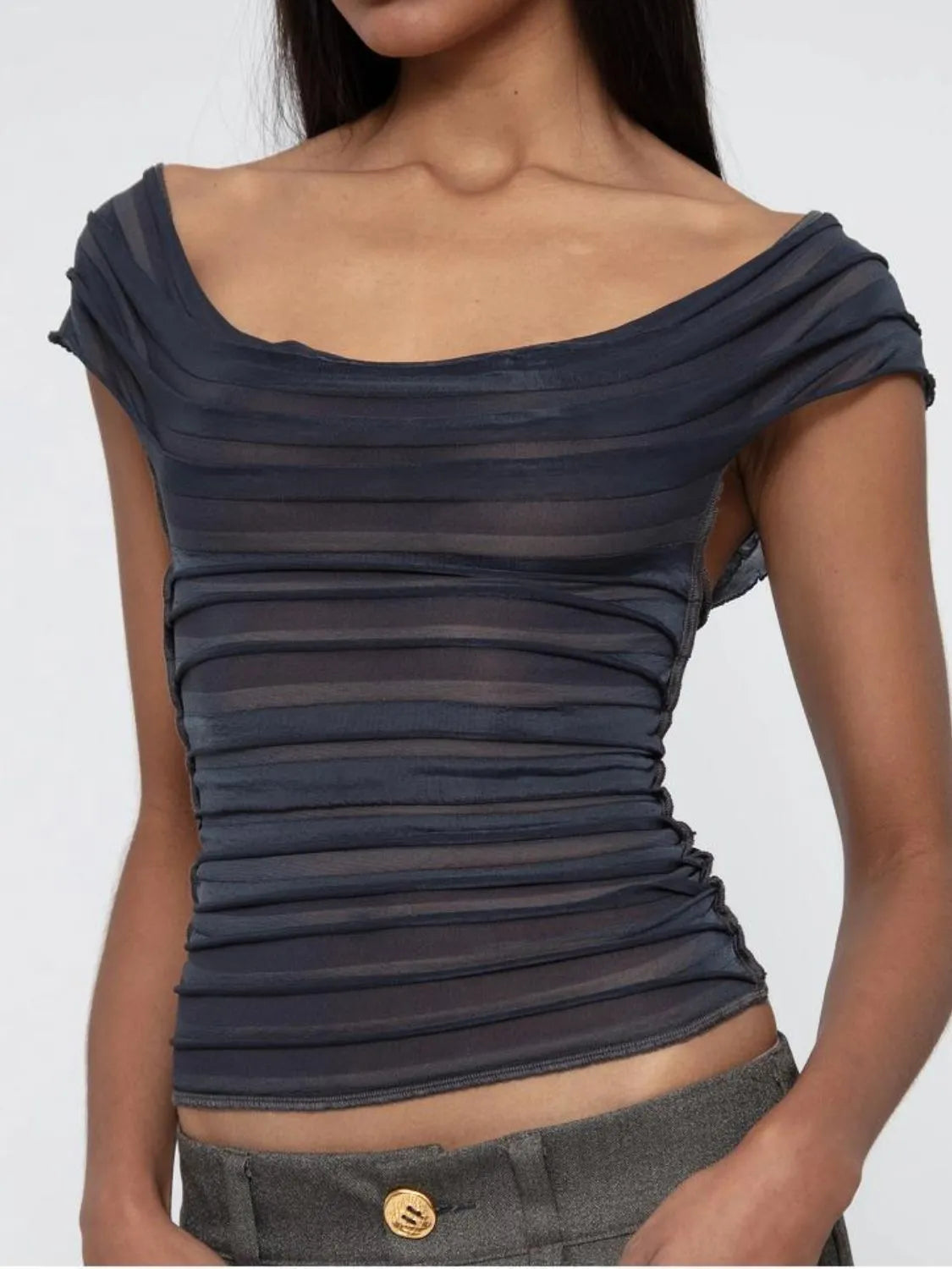 Woman wearing a dark gray off-shoulder ruched top against a white background