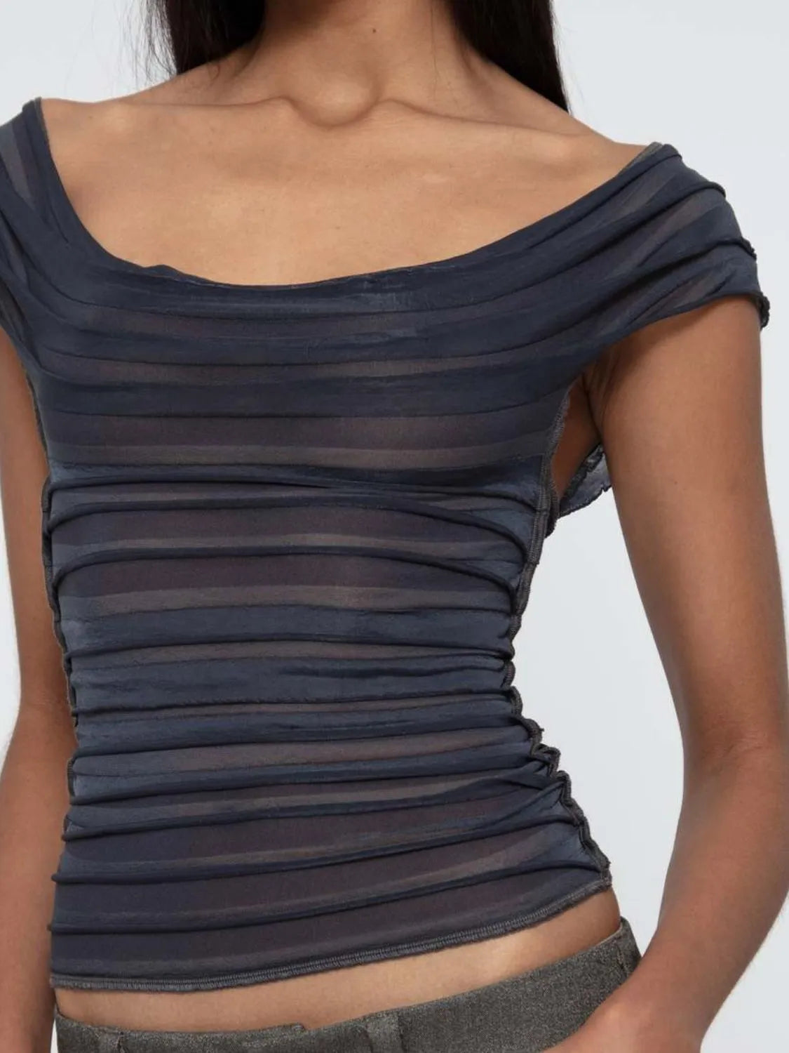 Dark gray off-shoulder ruched top worn by a woman on a plain background