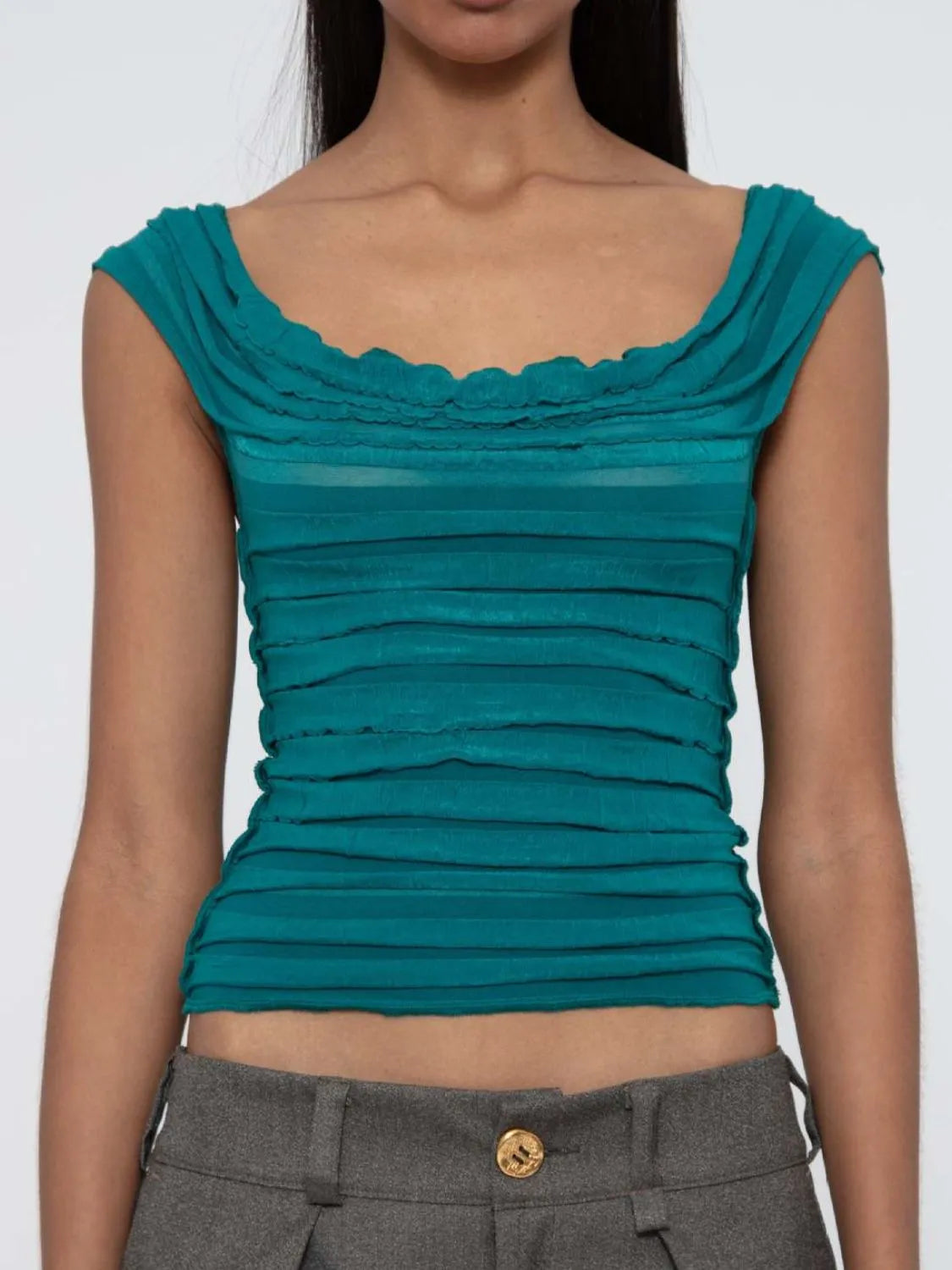 Teal sleeveless ruched top worn by a model on a white background