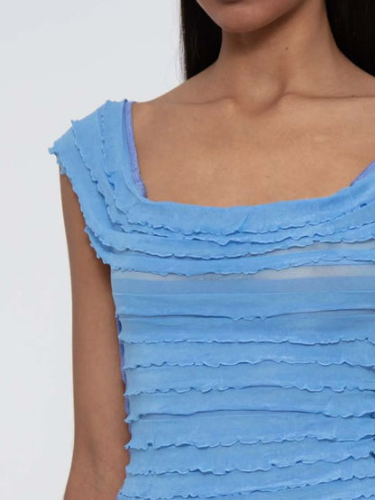 Close-up of a blue ruffled ruched sleeveless top worn by a woman against a white background