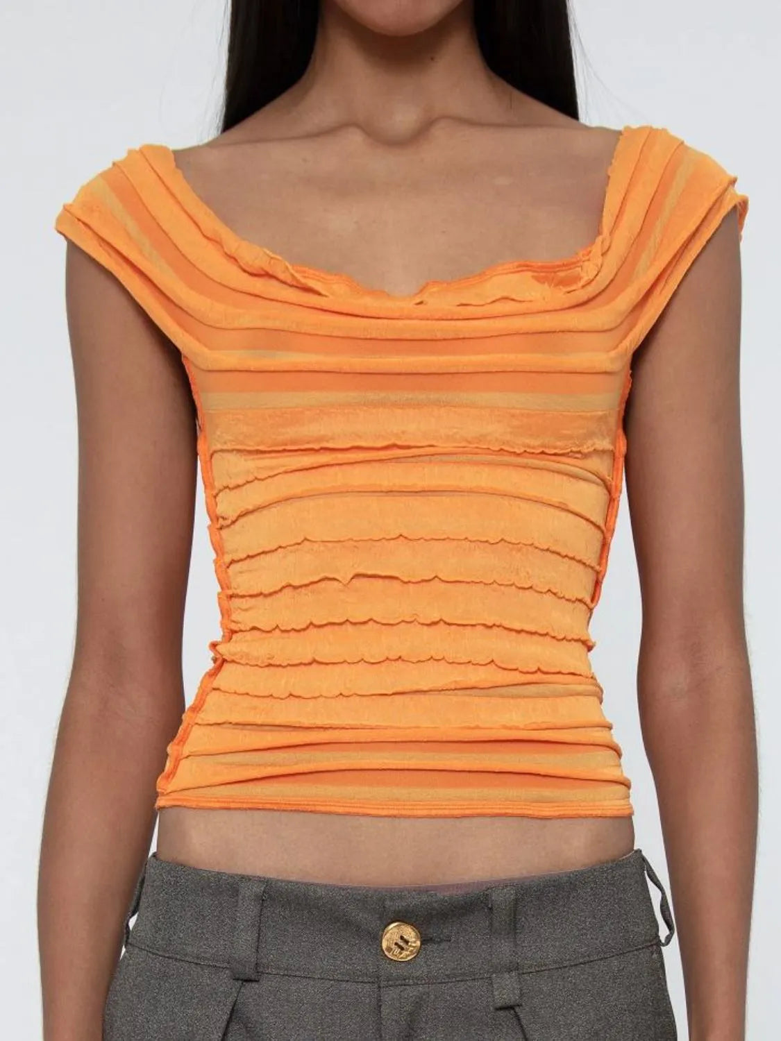 Orange ruched sleeveless top worn by a woman on a white background