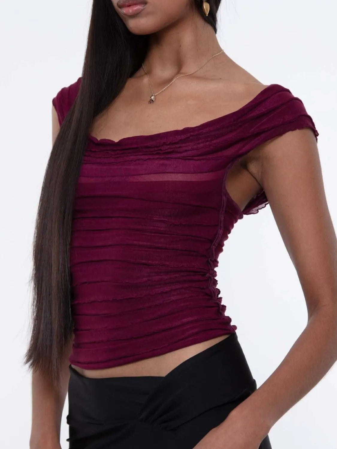 Woman wearing a purple off-shoulder ruched top against a white background