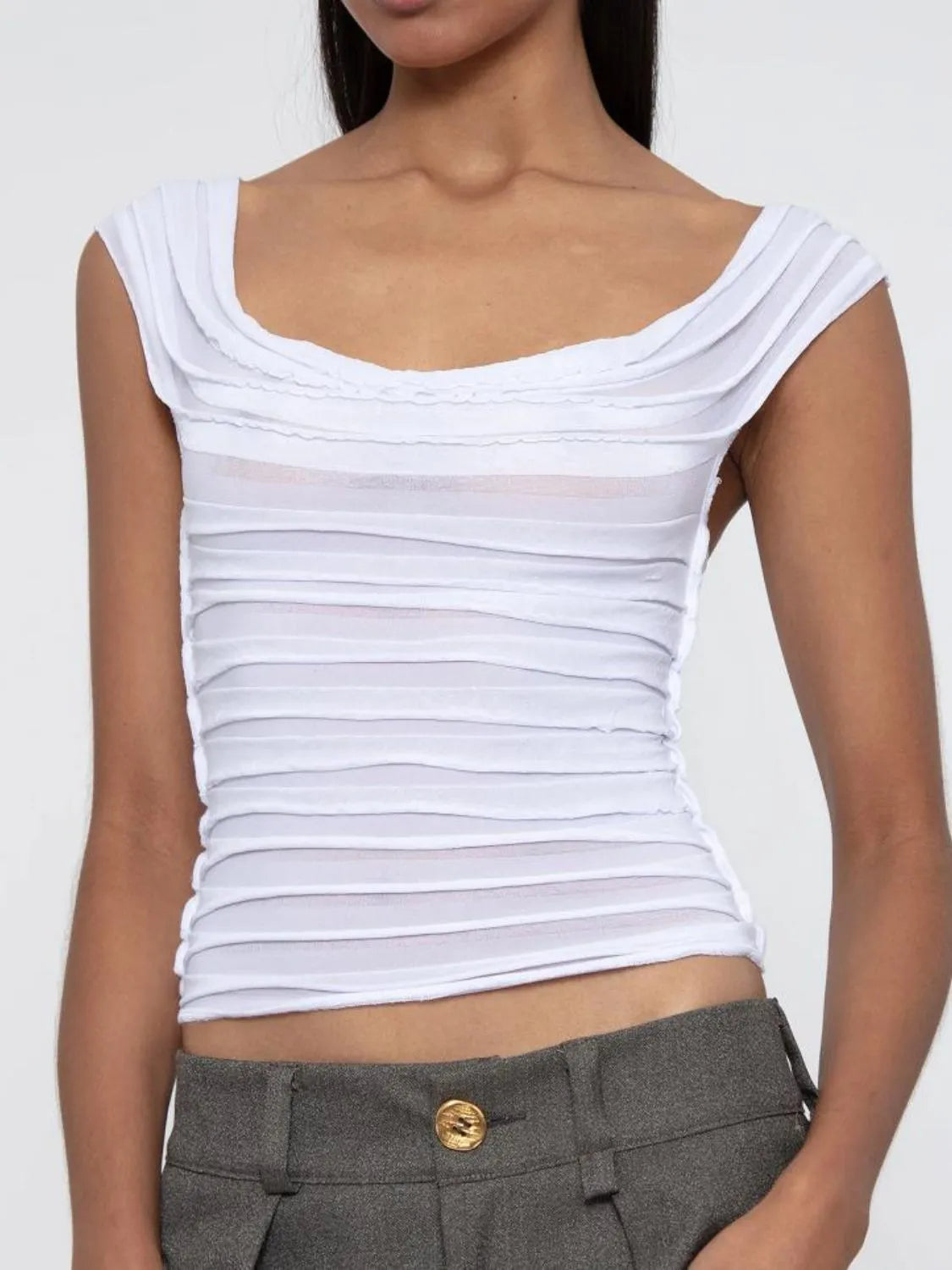White ruched sleeveless top worn by a woman on a plain background