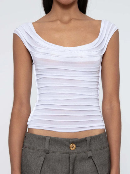 White sleeveless ruched top worn by a woman on a plain background