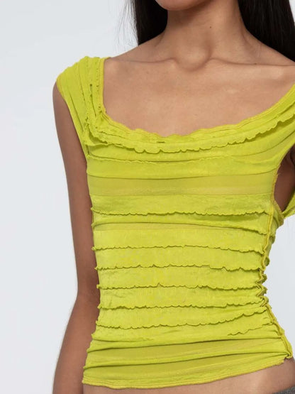 Yellow green sleeveless ruched top worn by a woman on a white background
