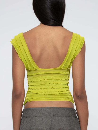 woman wearing a yellow green ruched sleeveless top back view with a plain background