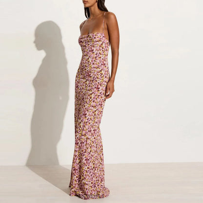 Side view of woman wearing a purple floral cami backless maxi  dress against a plain background