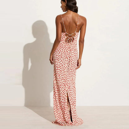 back view of woman wearing a red floral  maxi dress with backless lace up design on a white background