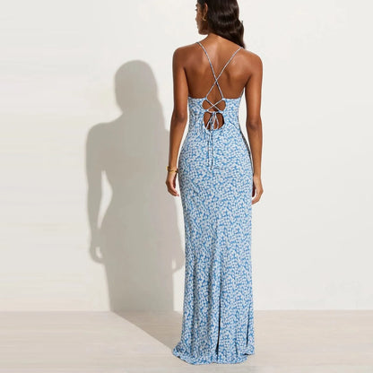 Back view of woman wearing a blue floral dress with a backless lace up design on a white background