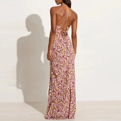 back view of woman wearing a purple floral dress with backless lace up design on a white background