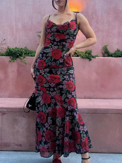 woman wearing a floral summer maxi dress with red roses against a pink wall.