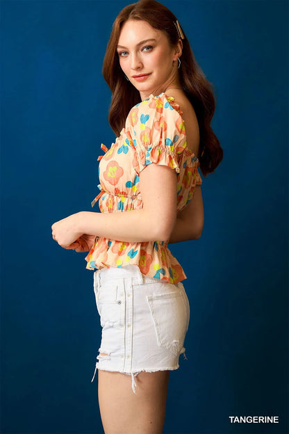 Woman wearing a vibrant floral Smocked Peplum Blouse side view 