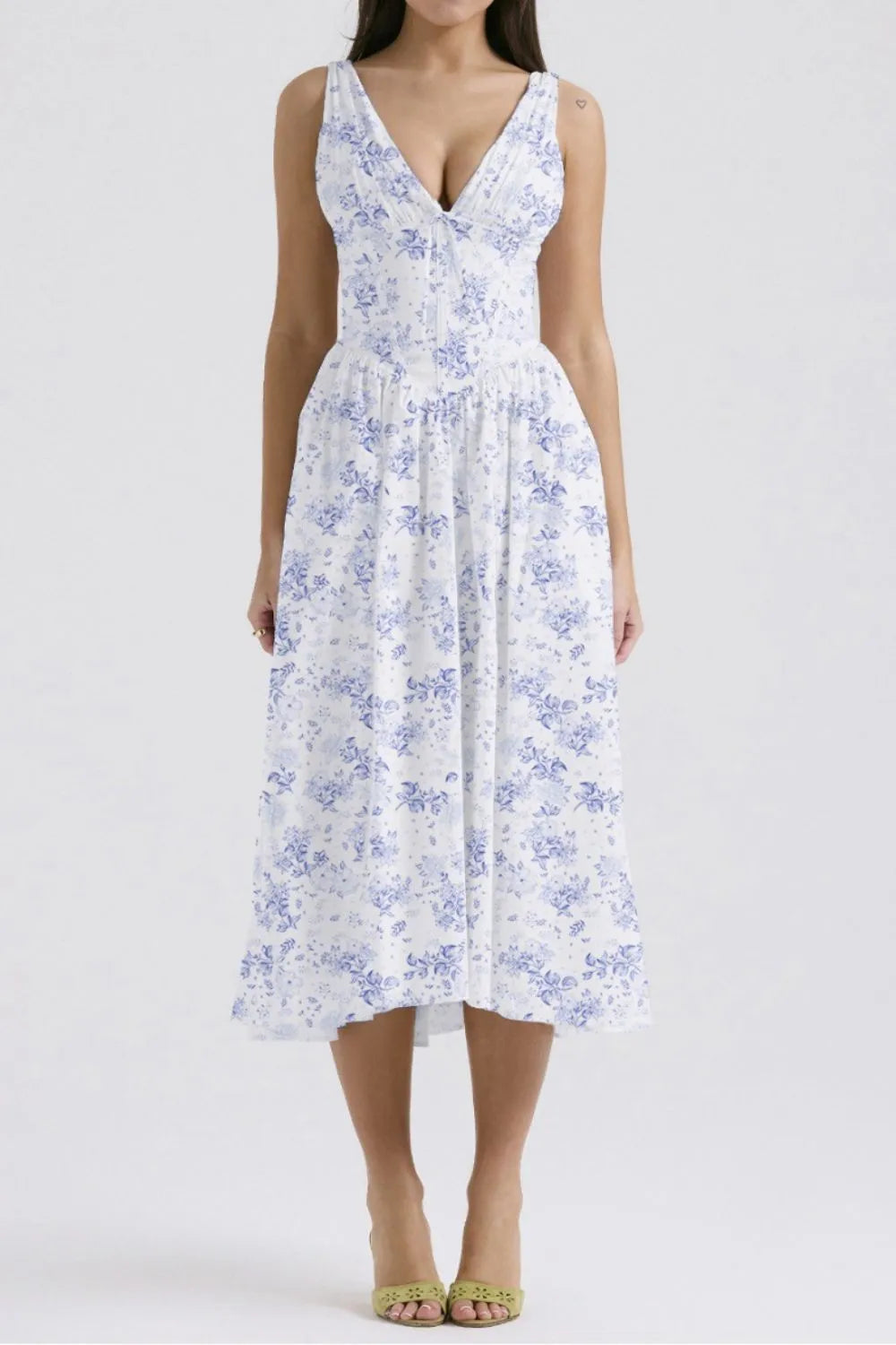 White sleeveless V-neck midi dress with blue floral pattern worn by a woman  on a white background