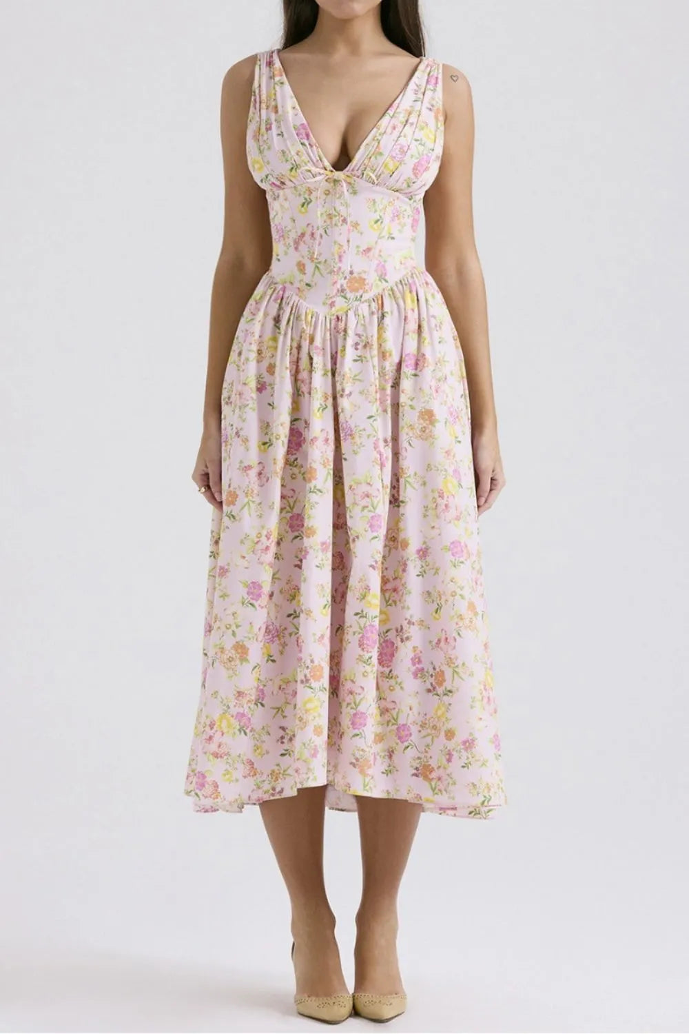 Woman wearing a pink floral casual summer midi dress with pockets on a white background