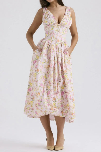 Woman wearing a pink floral v-neck midi dress with pockets on a white background