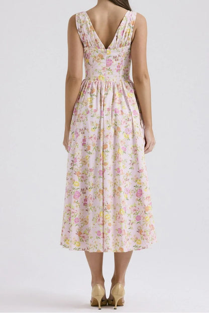 Back view of woman wearing a pink floral flowy midi dress on a white background