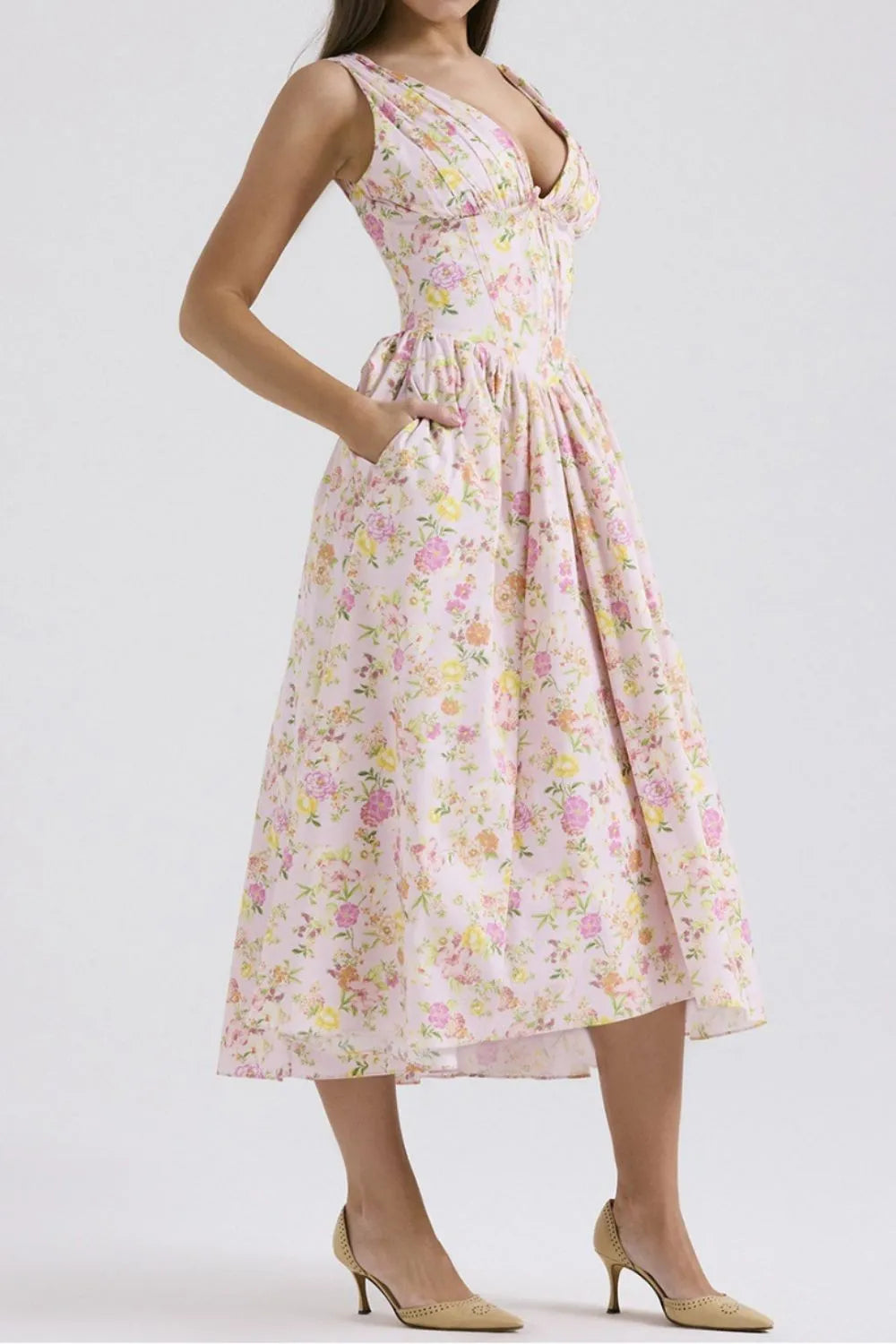 Woman wearing a pink floral v-neck midi dress side view on a white background