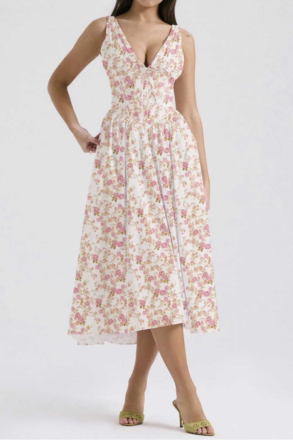 Woman wearing a white and pink floral flowy sleeveless v-neck midi dress with pockets on a white background