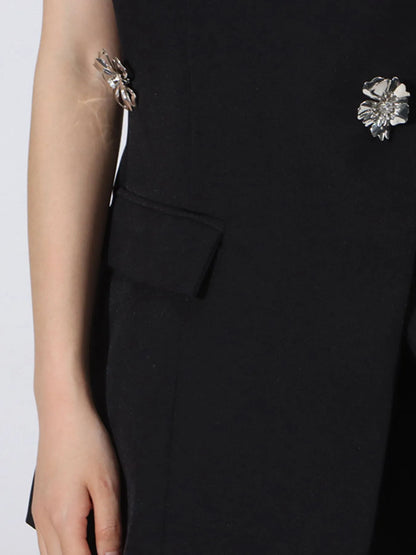 close up of black designer inspired blazer with floral brooches on a white background