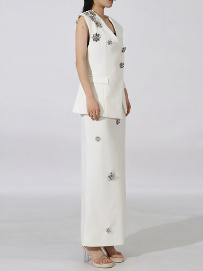 Side view of woman wearing a luxury floral sleeveless vest and maxi skirt set with floral embellishments on a plain background