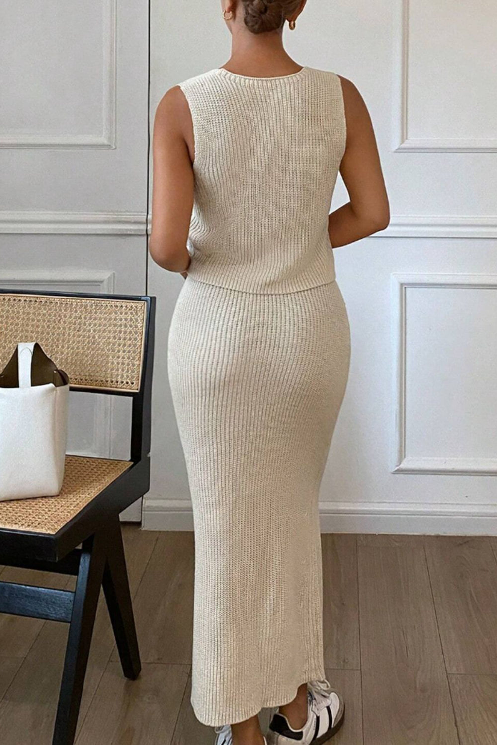 Women's floral V-neck vest and knit skirt sweater set in tan back view on model next to chair