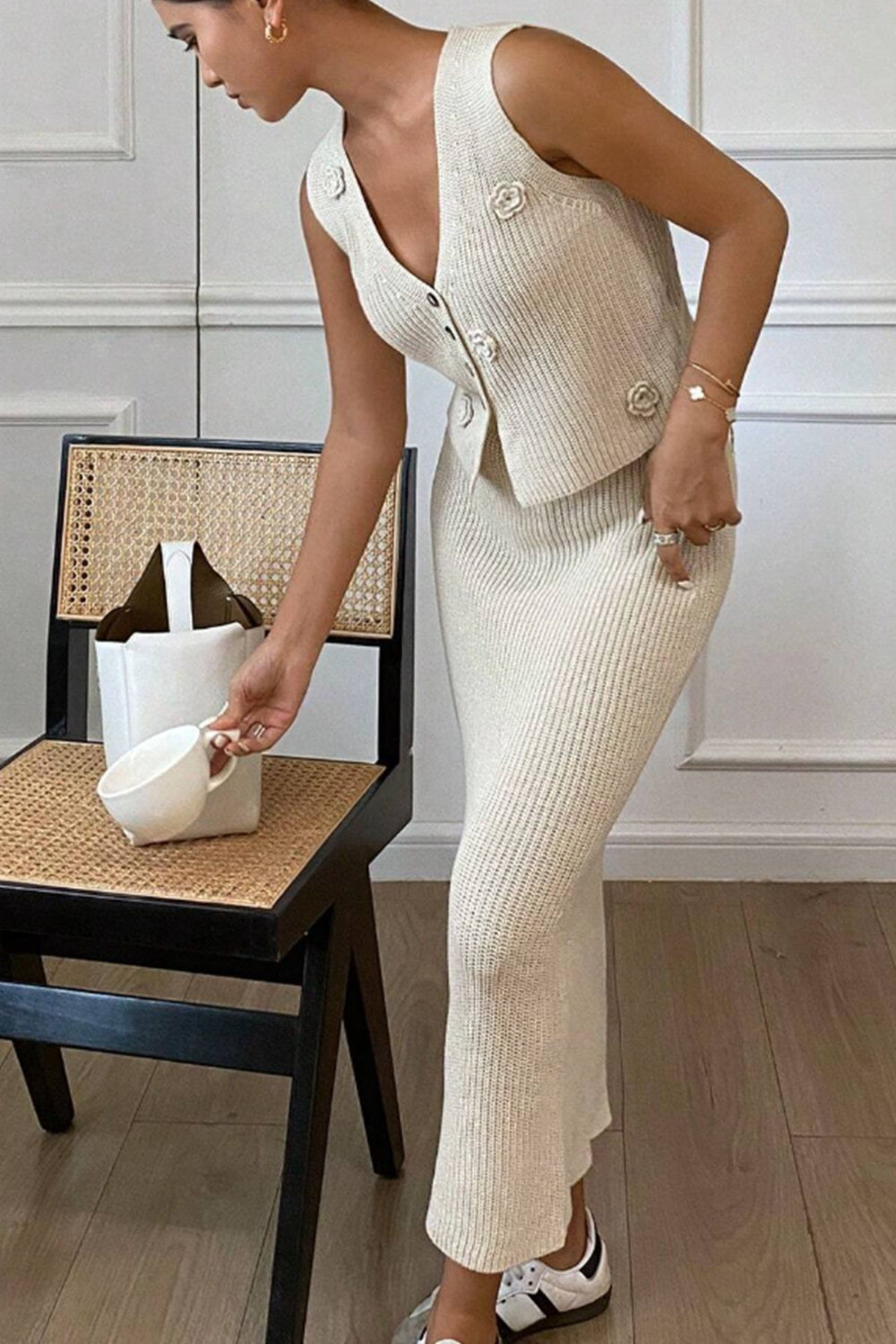 Women's floral V-neck vest and knit skirt sweater set in tan front view on model next to chair