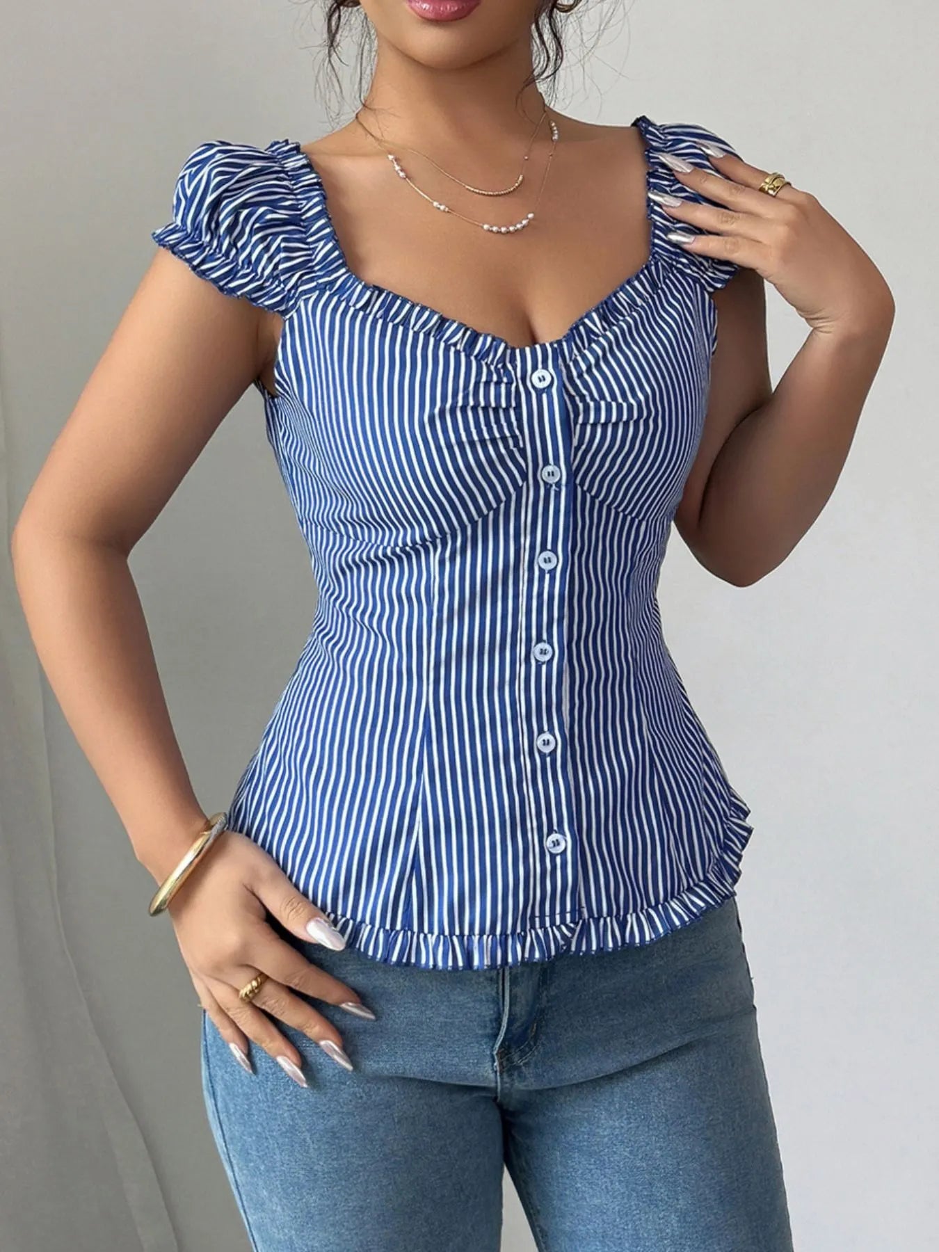 Woman wearing a blue and white striped frill top against a gray background
