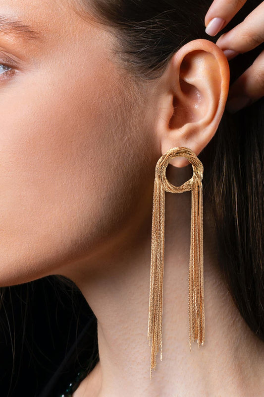 Woman wearing gold fringed round copper statement earrings 