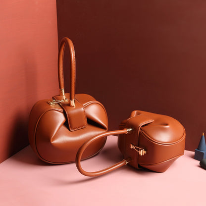 two brown leather dumpling handbag with a buckle closure and a single handle, displayed against a two-tone background 